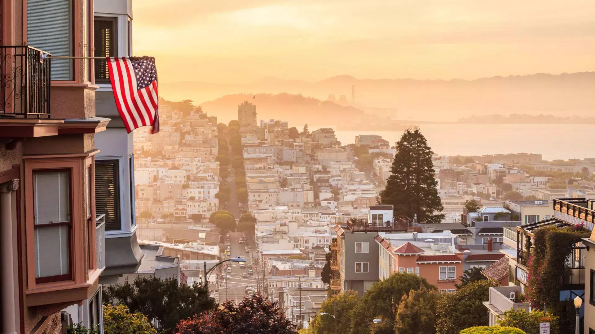 从山顶俯瞰贝博体彩app，前景中有一面美国国旗在飘扬.