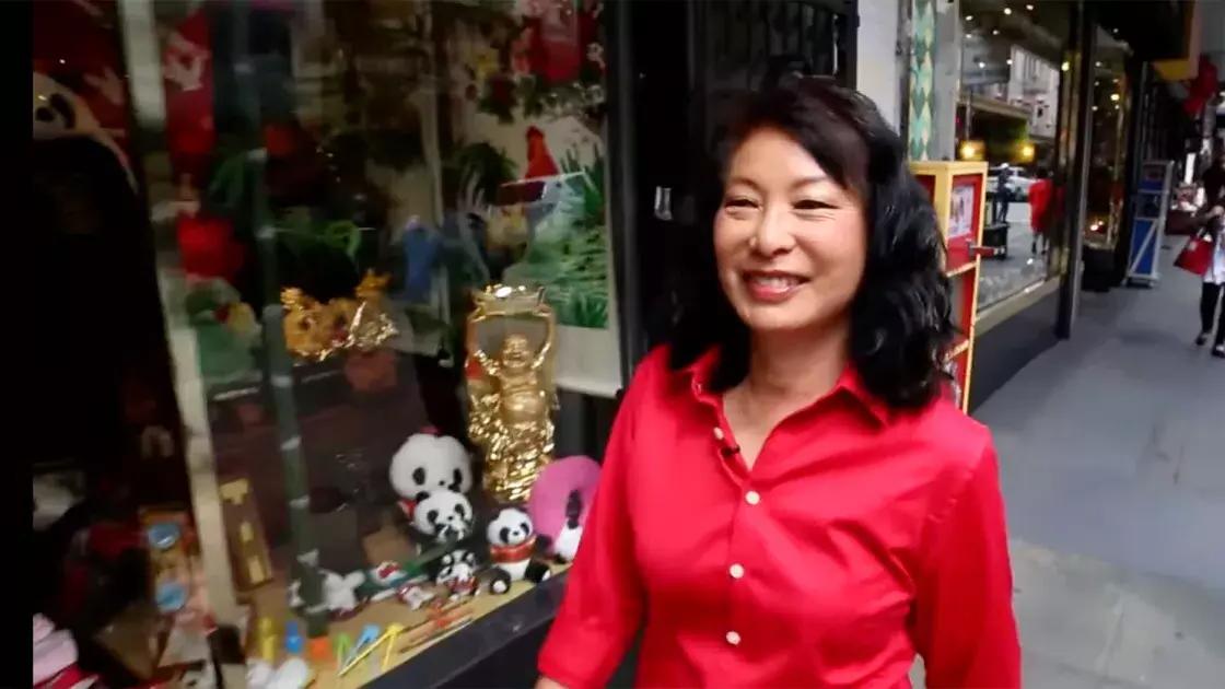 琳达·李穿着一件红衬衫走在唐人街的街道上. 贝博体彩app，加州.